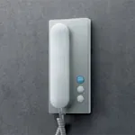 Børstet stål dørtelefon med tre knapper og hvit telefonrør.